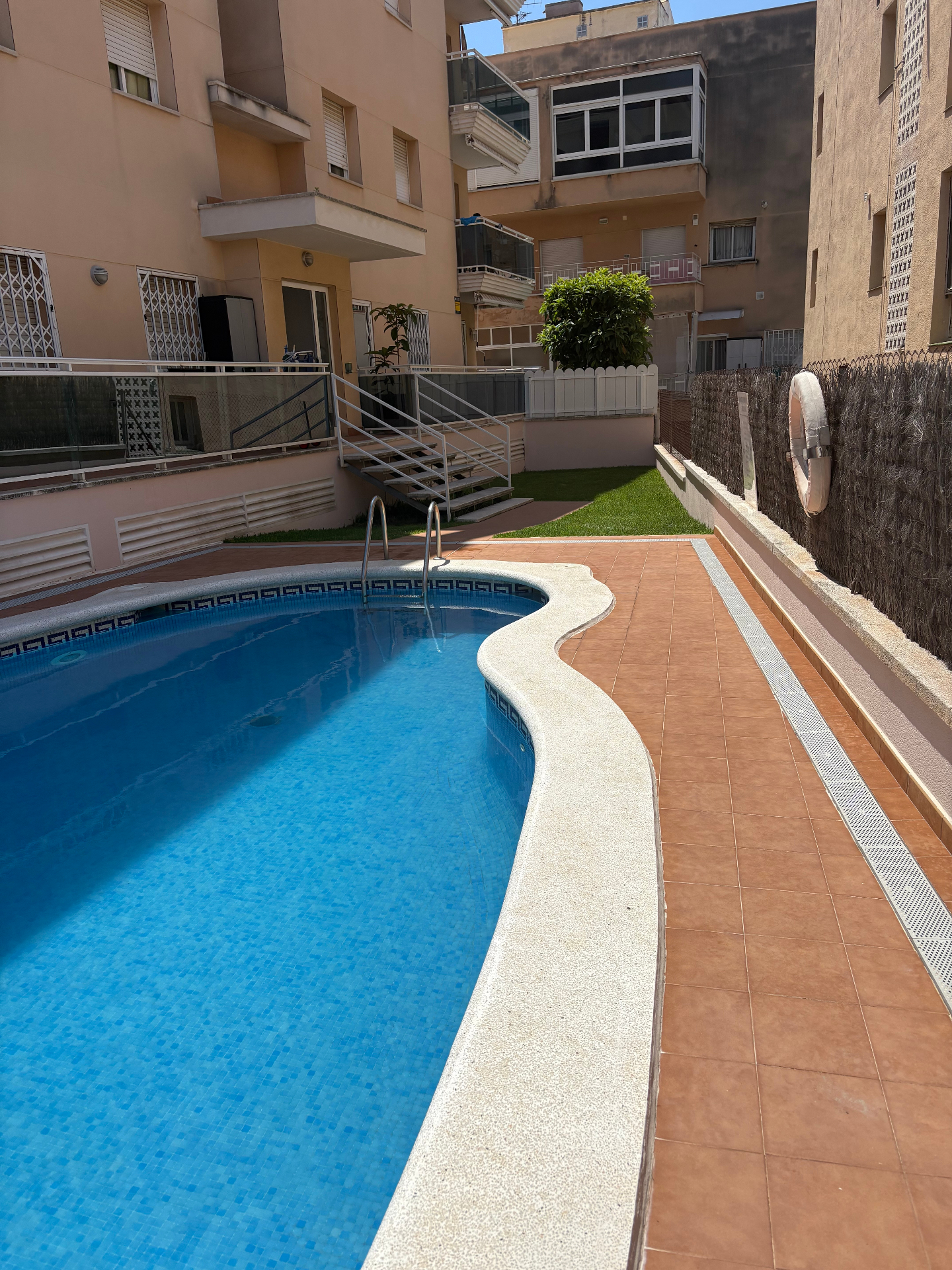 Piscina comunitaria del edificio con solárium y pocos vecinos